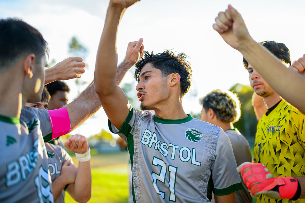 Men's soccer in a huddle with their fists up