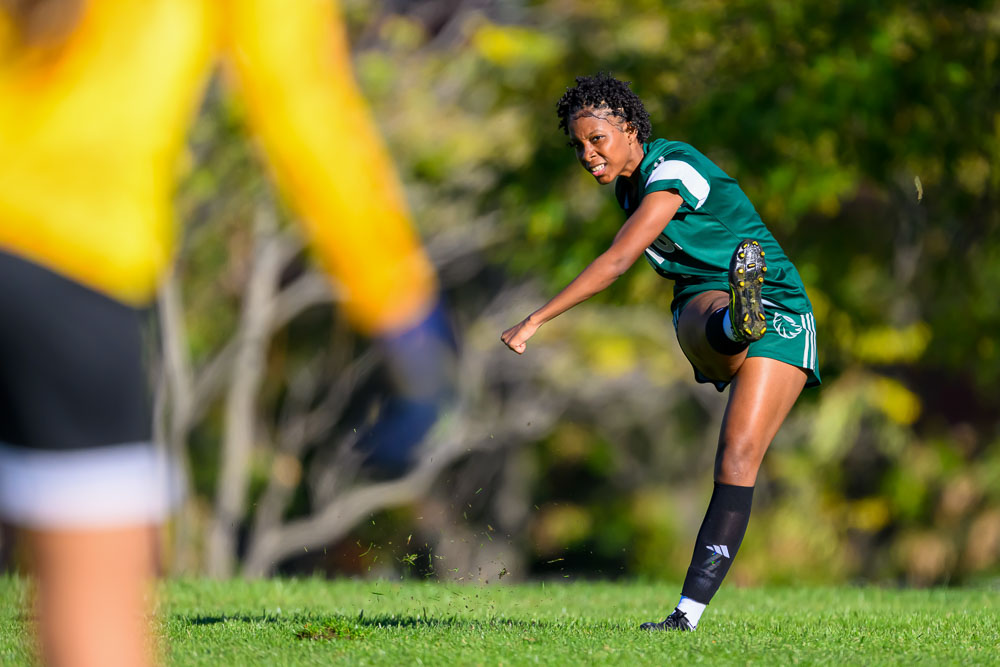 Woman with an intense expression kicking a soccer ball