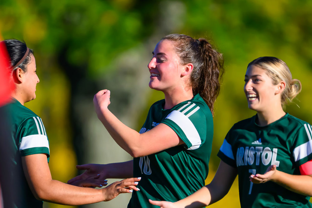 Women celebrating during soccer game. One has their arm flexed.