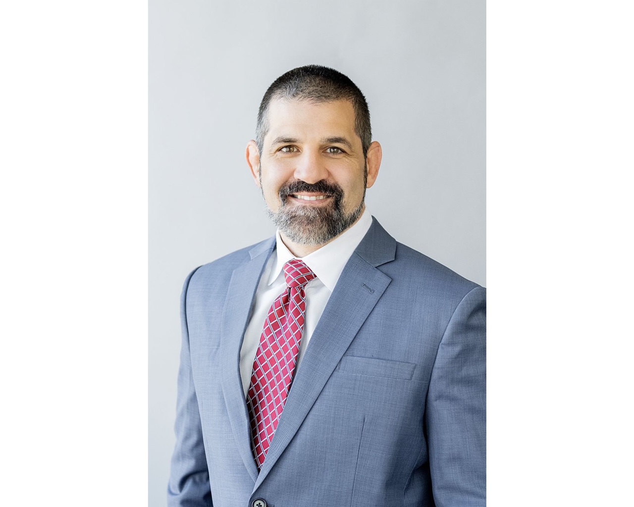 A man in a suit and tie smiles confidently, showcasing a professional appearance.