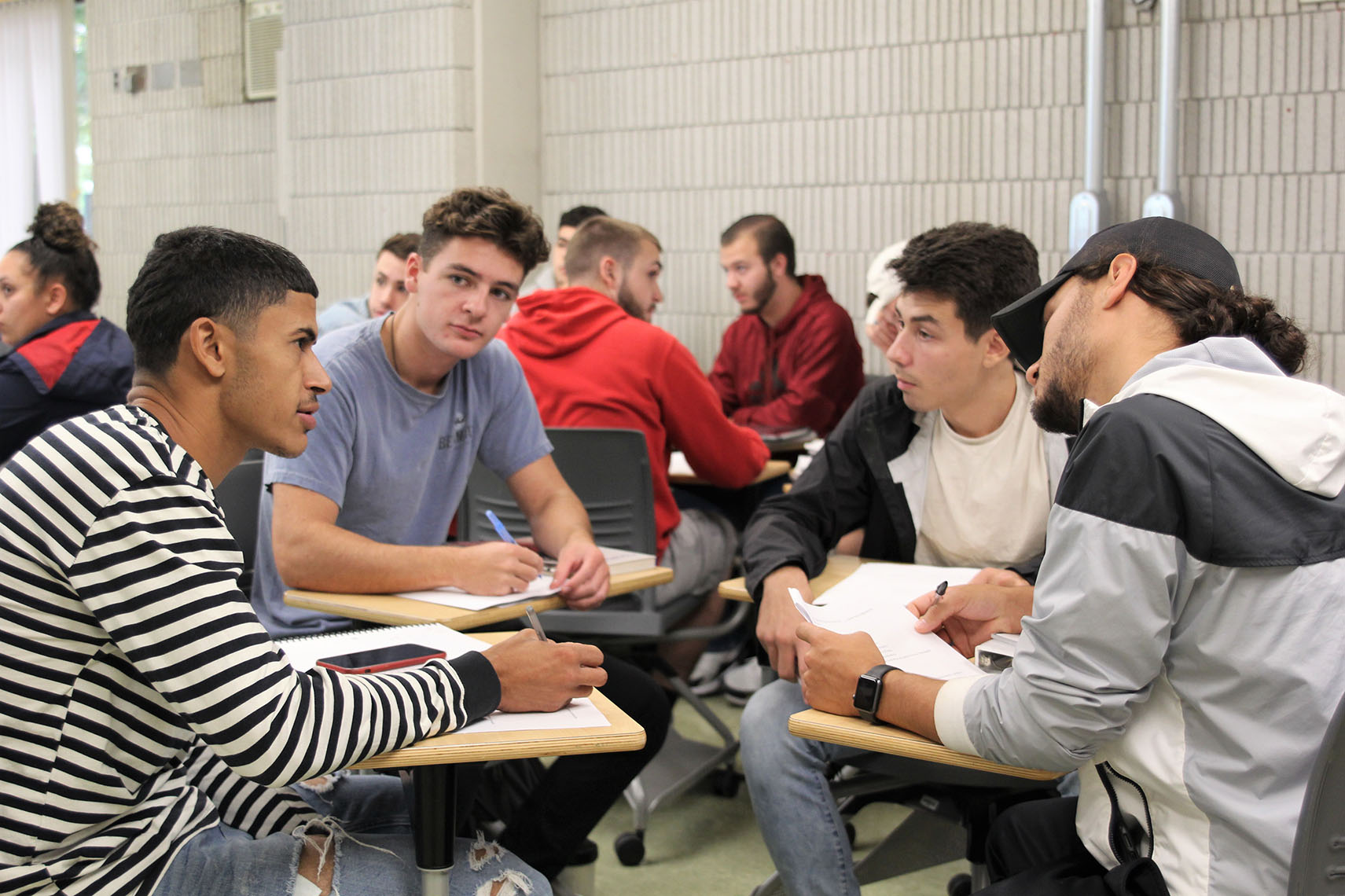 Students at desks sitting in a circle